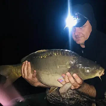 Ночная рыбалка на карпа с прикормочным корабликом фотография