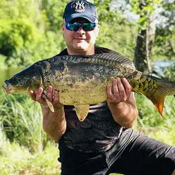 Трофейный карп - результат рыбалки с прикормочным корабликом фоторгафия